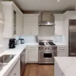 Modern kitchen sink and stainless steel oven with white marble countertops