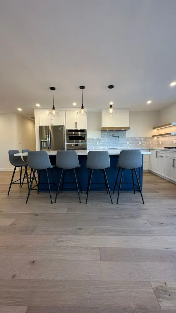 Modern kitchen addition in Los Altos with white cabinets, wood floors, island seating, and pendant lighting – Sigura Construction