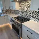San Jose kitchen remodeling project featuring stainless steel oven installation and custom black-and-white mosaic tile backsplash as part of a full fire damage restoration.