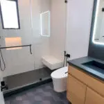 Sleek modern bath with hex gray tiles, black accents & floating vanity.