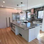 Sleek modern kitchen with marble island, matte black pendants, and walnut floors.
